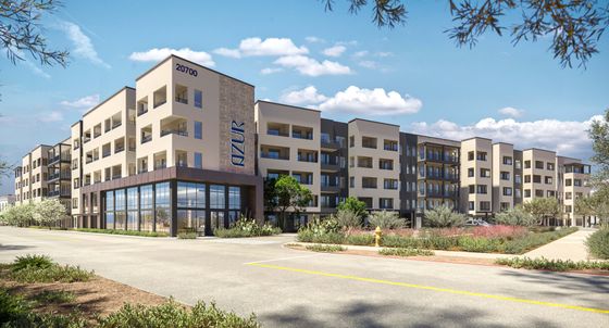 Contemporary five-story apartment complex with sleek design and lush landscaping, featuring numerous balconies under a sunny blue sky.