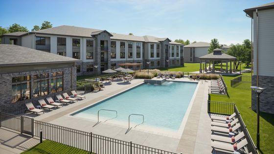 Luxurious apartment complex with pristine outdoor pool, cozy loungers, and scenic green spaces, perfect for relaxation and leisure.