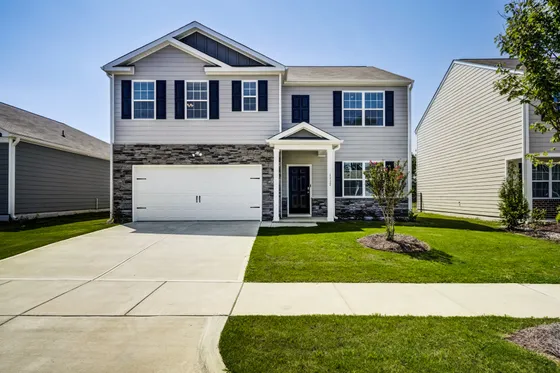 Charming two-story house with elegant stone facade, pristine driveway, and well-maintained front lawn, perfect for family living.