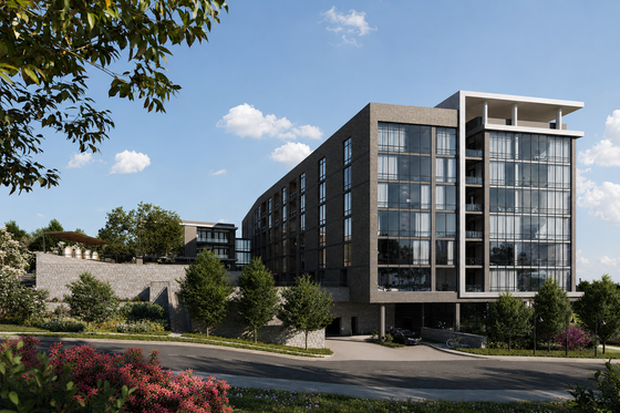 Modern apartment building with large glass windows, surrounded by lush greenery and vibrant landscaping.