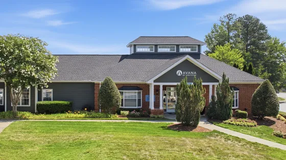 Inviting apartment complex entrance with lush landscaping and elegant brick facade, offering a serene living environment.