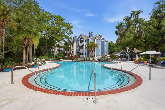 Inviting resort-style swimming pool surrounded by lush greenery and modern apartments, perfect for relaxation and leisure.