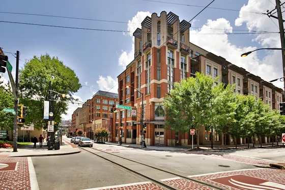 Charming urban apartment building with modern architecture on a vibrant, tree-lined street corner.