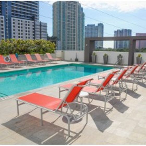 Brickell First Luxe City Rentals, exterior, sparkling blue pool, orange lounge chairs,