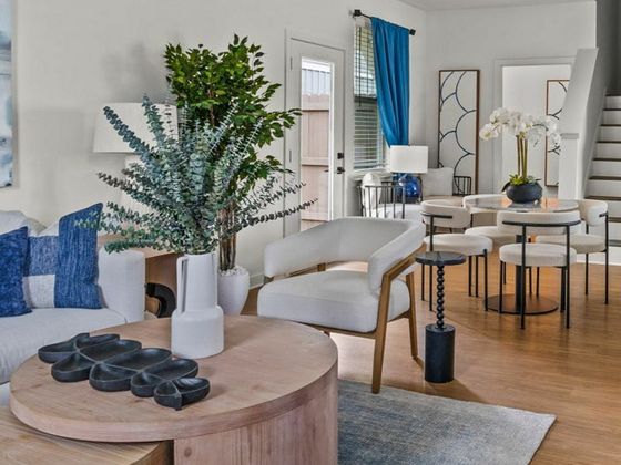 Chic living and dining area with modern decor, featuring a cozy seating arrangement, elegant stairs, and vibrant accents.