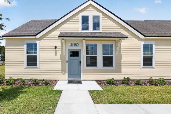 Charming yellow single-story home with a lovely blue front door, manicured lawn, and inviting walkway.
