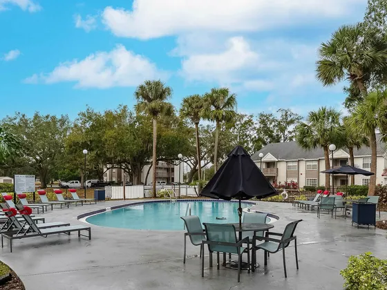 Inviting outdoor pool area surrounded by lush greenery and modern lounge chairs, perfect for relaxation and leisure.