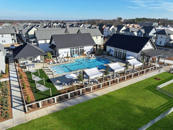 Vibrant community aerial view showcasing a luxurious pool area with stylish shaded seating, surrounded by modern buildings and lush greenery.