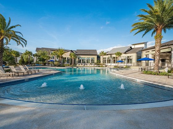 Luxurious apartment complex showcasing a serene pool surrounded by lush palm trees and elegant lounge areas, perfect for relaxation and leisure.