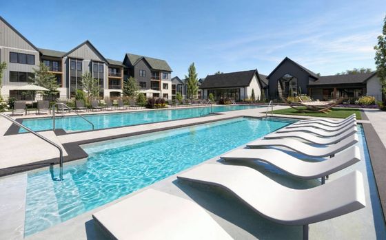 Elegant outdoor swimming pool surrounded by modern apartment buildings with sun loungers and lush landscaping.