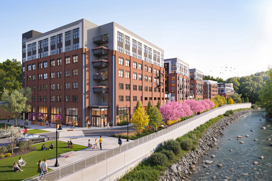 Charming riverside apartment complex with modern brick architecture, vibrant landscaping, and a scenic pathway along the water.