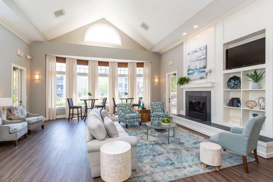 Bright and spacious clubhouse with modern furnishings, large windows, and a cozy fireplace.