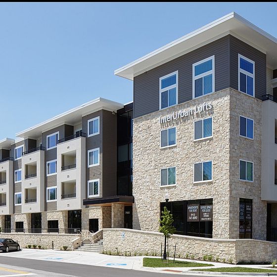 Exterior view of InterUrban Lofts, a four-story modern mixed-use building with stone and metal panel facade in downtown Overland Park