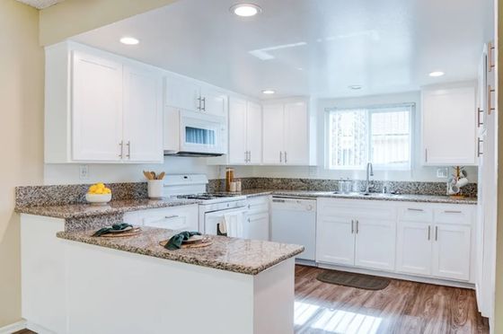 Bright and modern kitchen with sleek white cabinets, granite countertops, and stainless steel appliances.