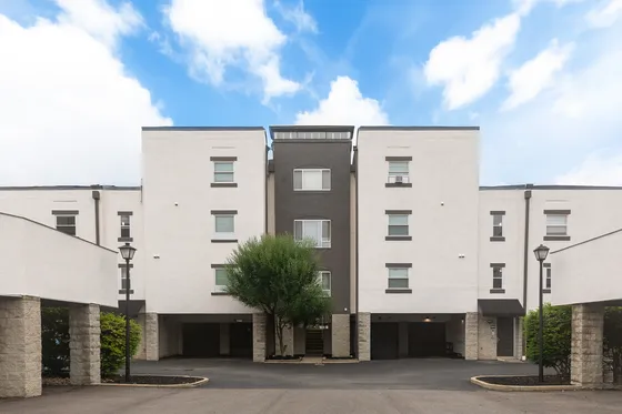 Contemporary apartment building exterior with clean lines, featuring modern architecture and lush landscaping under a vibrant blue sky.