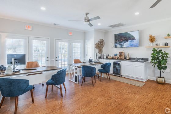 Modern office space with stylish decor, featuring wooden flooring, plush chairs, and elegant lighting.