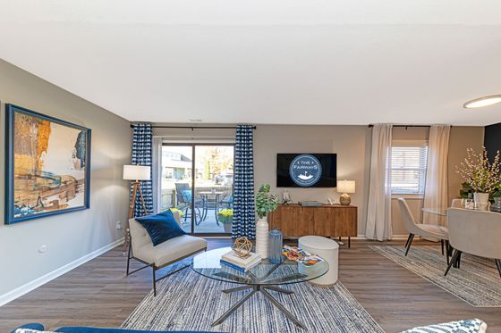 Elegant living room with contemporary decor, large glass table, cozy seating, and outdoor patio access.