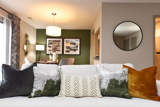 Stylish living room with a plush white sofa, decorative pillows, and elegant art on green accent wall.