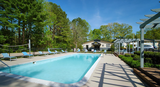 Inviting outdoor pool area with sun loungers, surrounded by lush greenery on a sunny day.