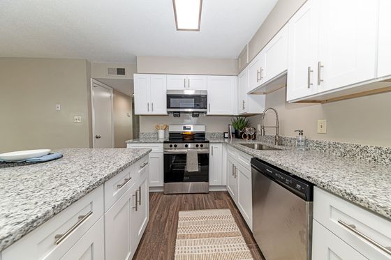 Modern kitchen with sleek granite countertops, white cabinetry, and stainless steel appliances, offering a stylish and functional cooking space.