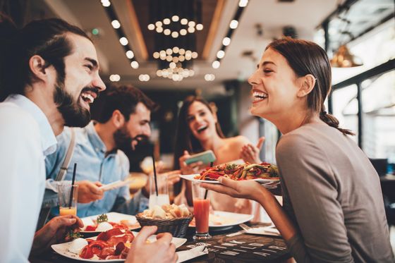 Group of friends enjoying a lively meal in a modern restaurant, featuring vibrant decor and delicious dishes.