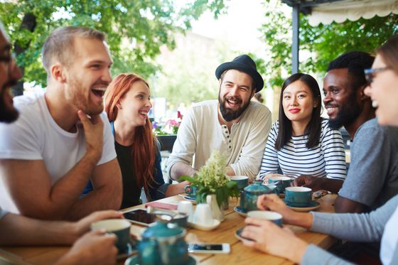 Vibrant group of friends enjoying coffee and laughter in a lively outdoor cafe setting.