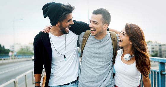 Three friends joyfully walking together on a sunny day, exuding happiness and camaraderie.