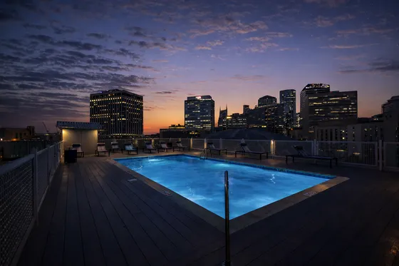 Stunning rooftop pool with breathtaking city skyline views at dusk, perfect for relaxation and luxury living.