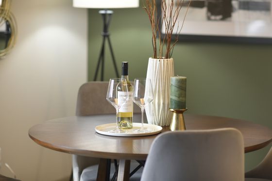 Chic dining table setup with wine bottle, glasses, and elegant decor, set against a stylish interior backdrop.