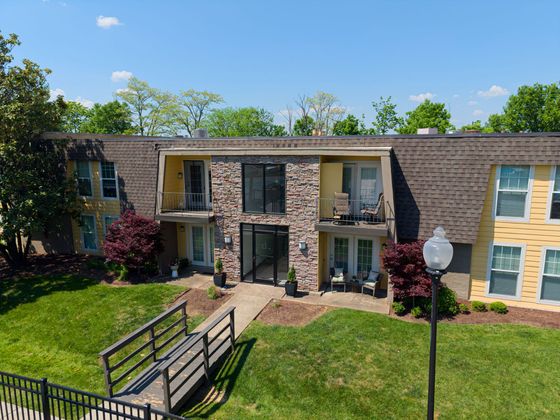 Charming apartment building showcasing a welcoming entrance, lush greenery, and cozy balconies under a bright blue sky.