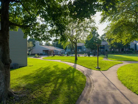 Charming outdoor community space with lush greenery, winding paths, and cozy patio seating.