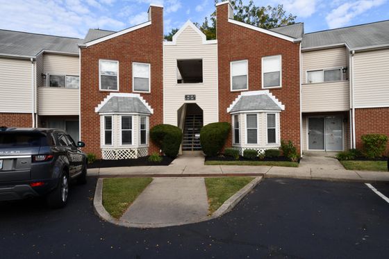 Charming brick apartment building with distinctive bay windows, lush landscaping, and convenient parking.