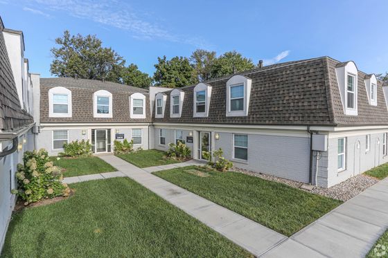 Charming residential complex featuring modern two-story buildings with attractive brown shingle roofs and manicured lawns.
