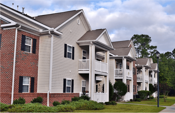 Charming apartment complex with elegant balconies, classic brickwork, and lush green surroundings.