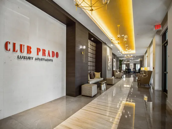 Elegant lobby of Club Prado Luxury Apartments featuring modern seating, ambient lighting, and polished marble flooring.