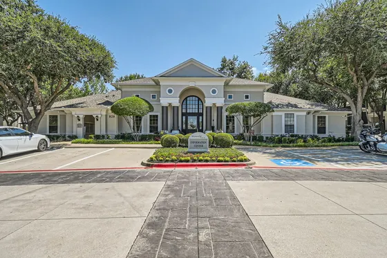 Elegant apartment complex entrance surrounded by manicured landscaping and welcoming sidewalks.