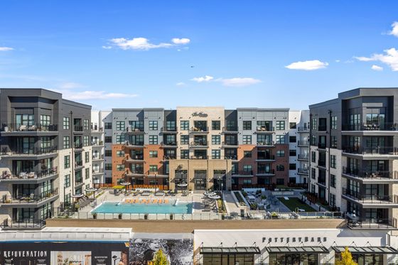 Chic urban apartment complex with modern architecture and inviting courtyard pool, surrounded by lush landscaping and bright outdoor seating.