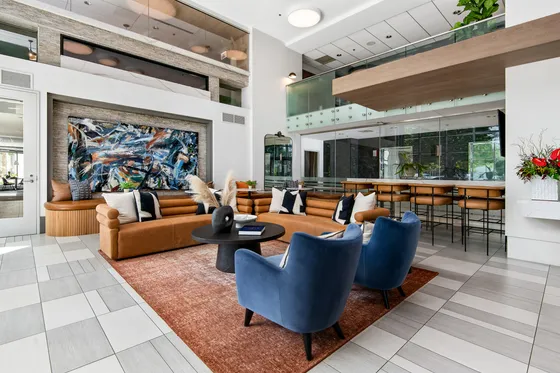 Modern open-concept living area with vibrant artwork, stylish seating, and sophisticated bar setup.