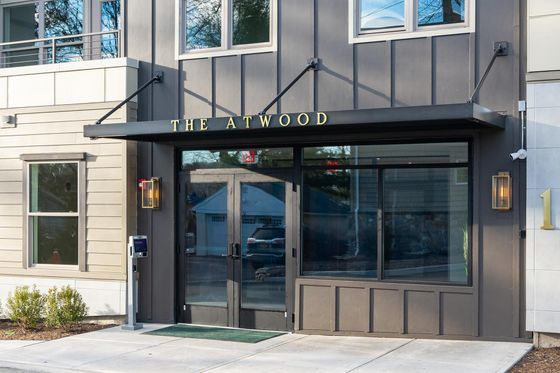 Welcoming entrance of The Atwood, stylish modern exterior with glass double doors and elegant signage.