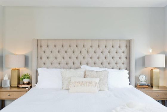 Beautiful queen bed with being and white bedding and quilted headboard.