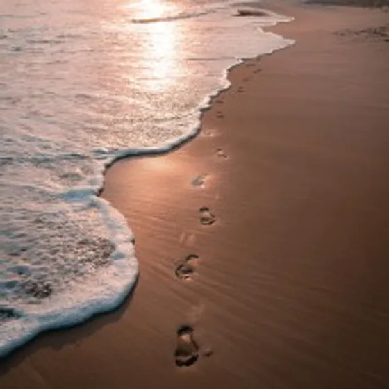 Footprints along a beach with surf rolling in.