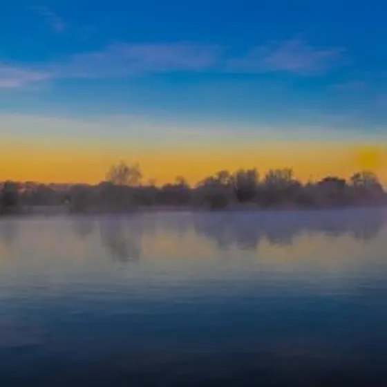 River with sunset sky and trees in the backdrop.