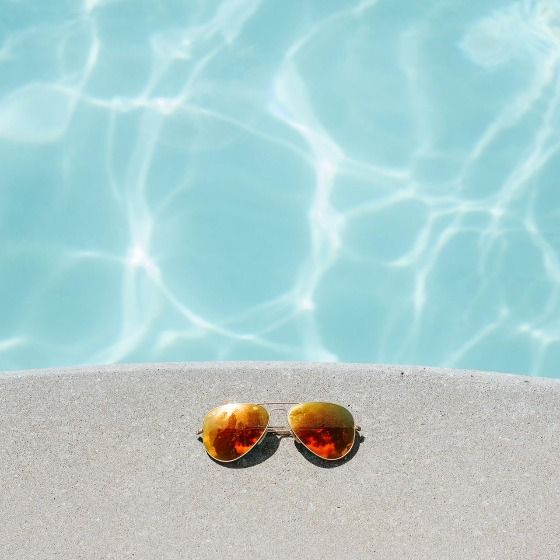 Sunglasses next to a swimming pool
