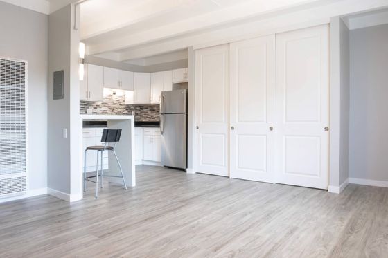 Kitchen with white cabinets, black counter and multi color tile backplash.