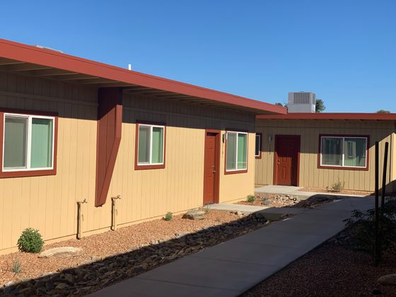 Sand color apartment building with rust colored doors. Desert landscaping.