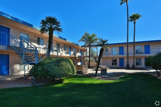 blue doors and sand colored exterior of building. garden style landscaping with palm trees and blue skies