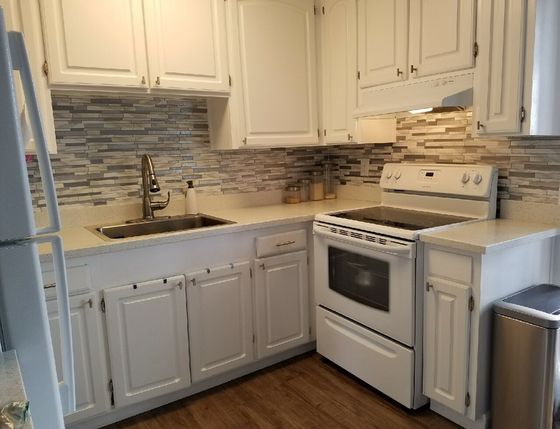 Kitchen with white cabinets, stove top and gooseneck faucet
