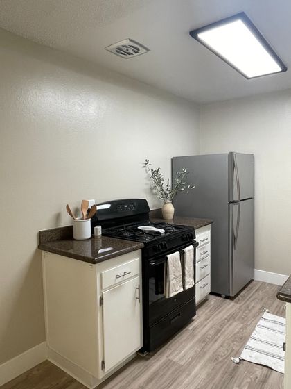 Small corner of a kitchen with fridge, stove and kitchen utensils
