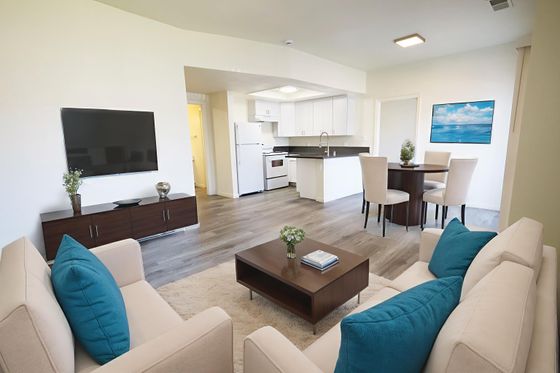 Staged living room with hard surface flooring and view of kitchen with white cabinets