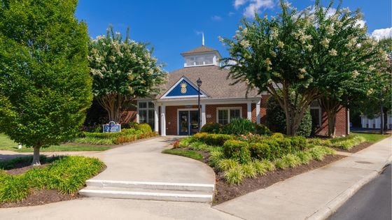 Inviting brick building with charming landscaping and a welcoming front path, set under a bright blue sky, ideal for a serene residential experience.